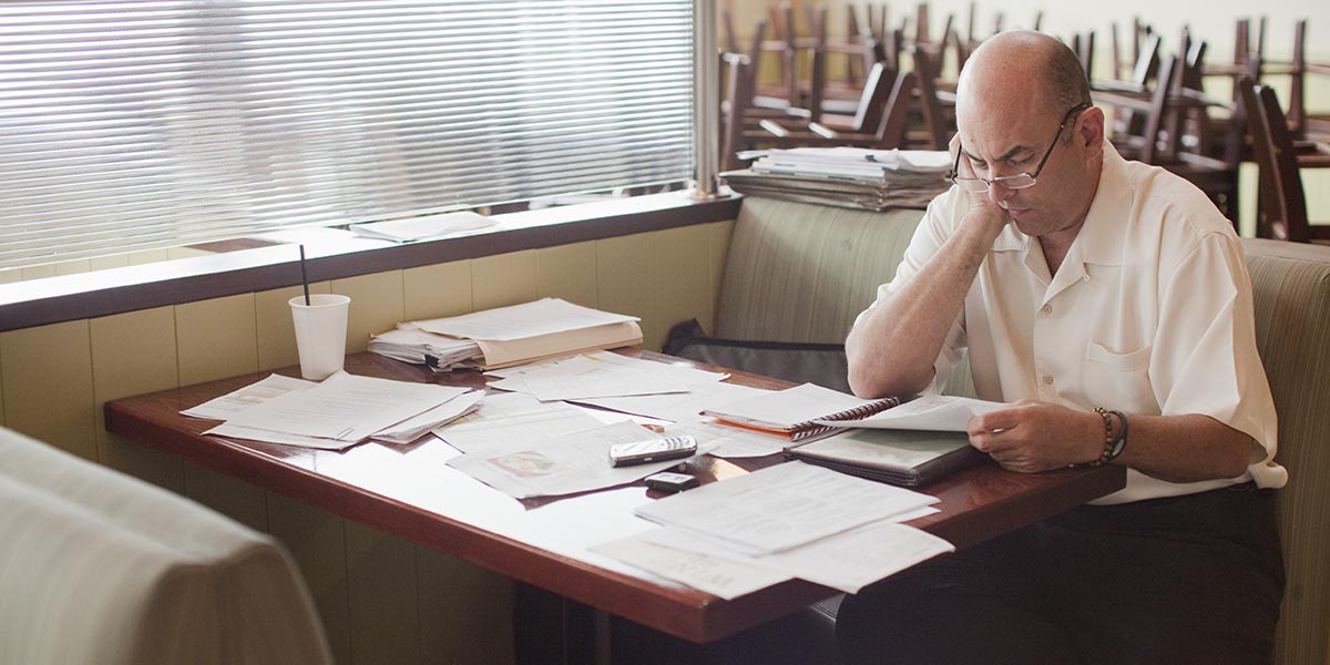 restaurant owner looking at paperwork in an empty restaurant